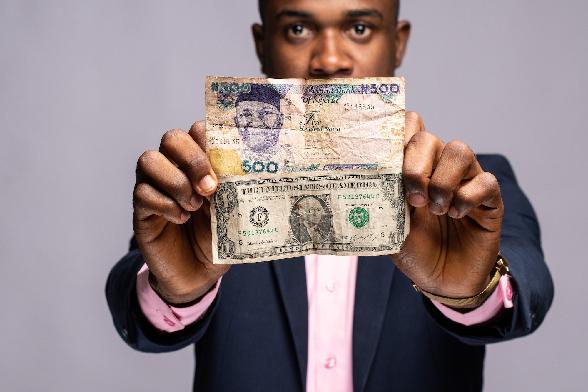 man holding naira and dollar bills