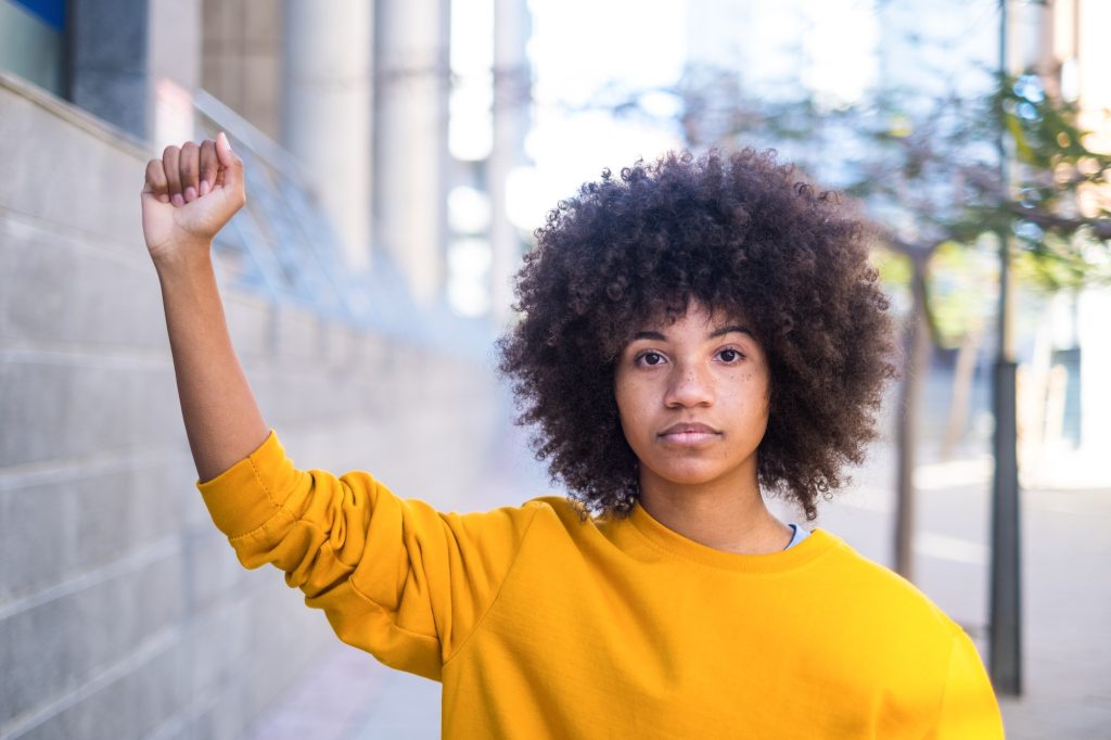 Black Lives Matter concept. One serious young african or american woman with her arm up